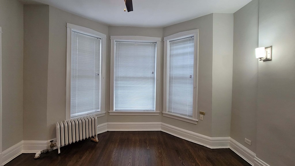 a living room with three windows and a radiator
