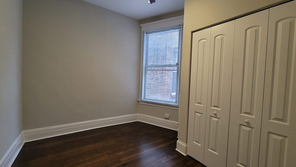 a bedroom with two closet doors and a window