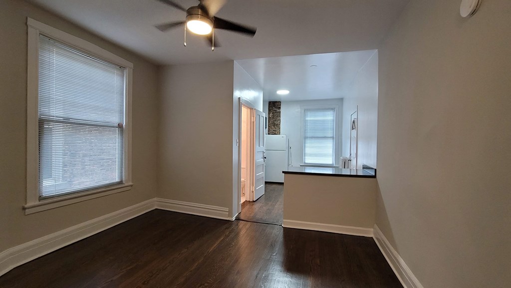 a living room with a large window and a ceiling fan