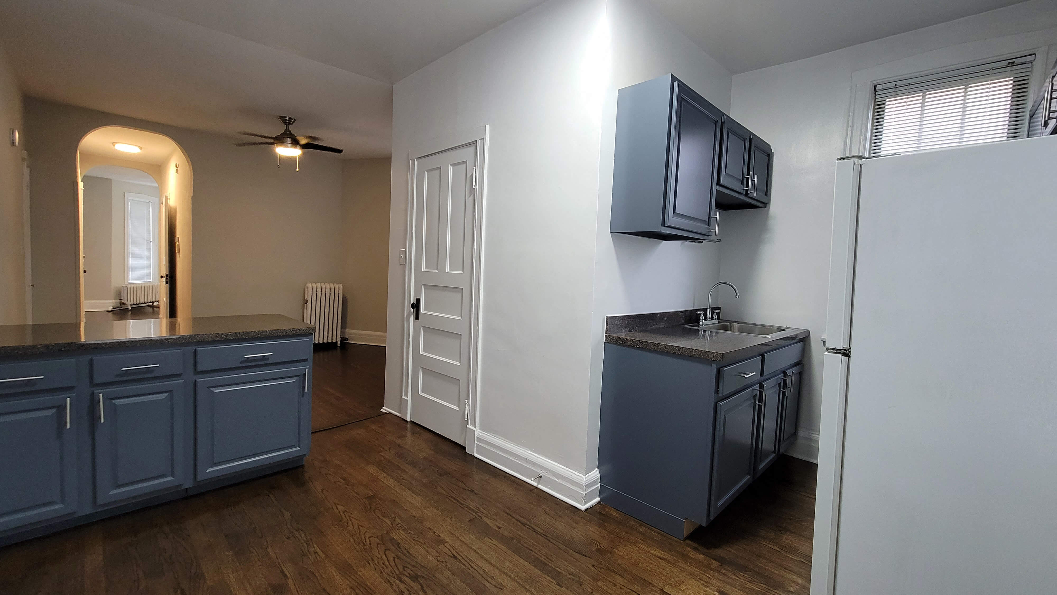 an empty kitchen with blue cabinets and a refrigerator