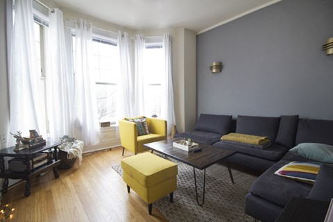 a living room with a blue couch and yellow chairs