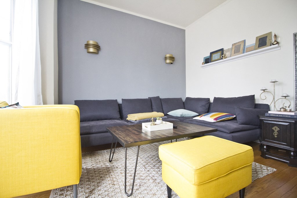 a living room with blue couches and yellow chairs and a table