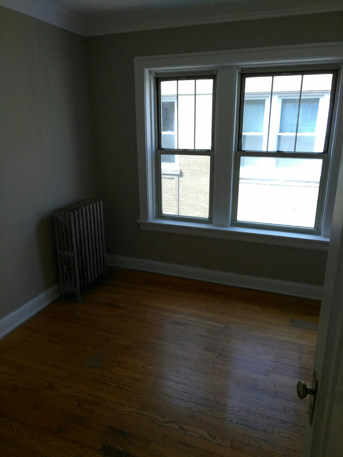 an empty room with a radiator and two windows