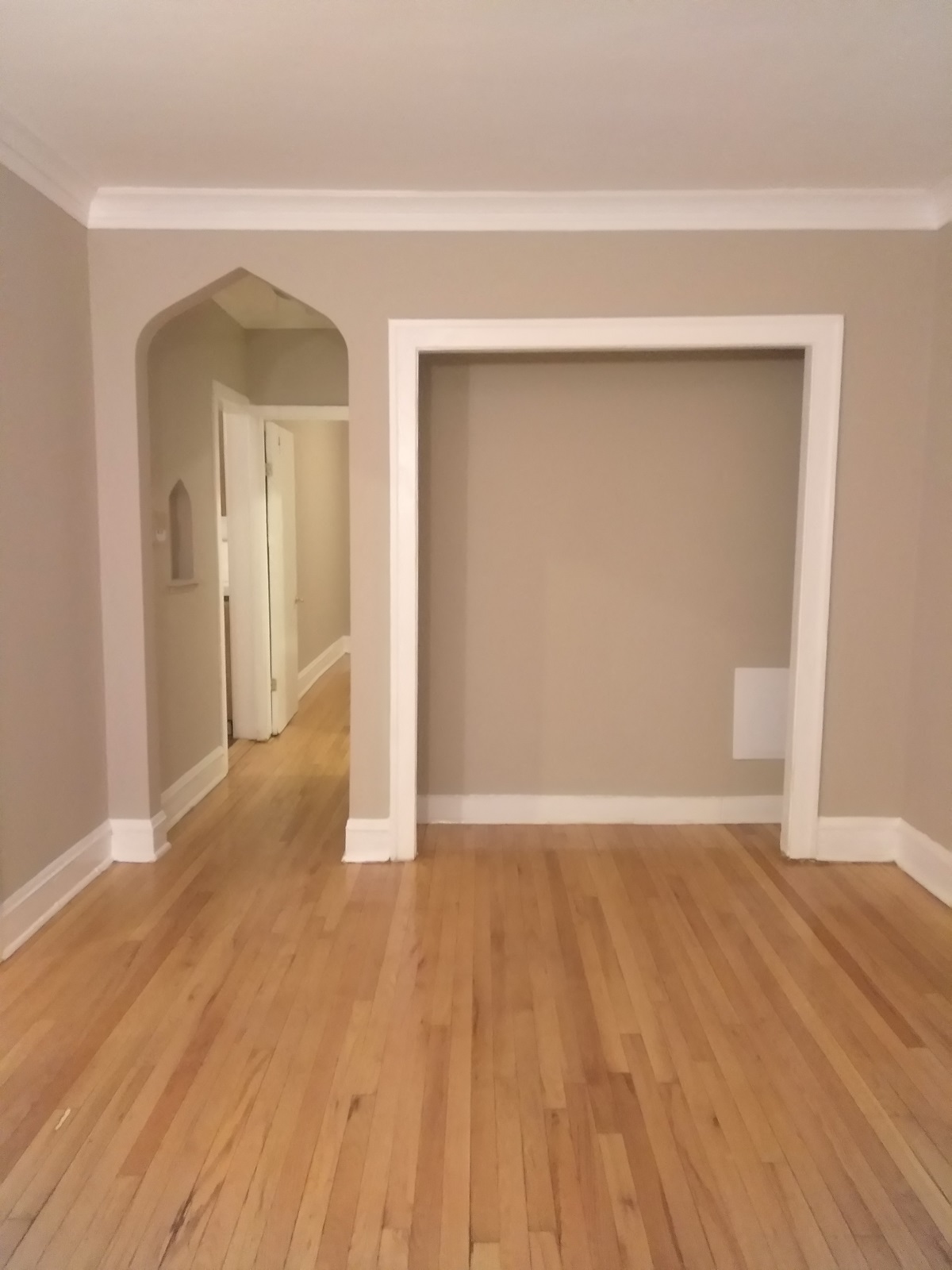 an empty living room with a wooden floor and an open doorway