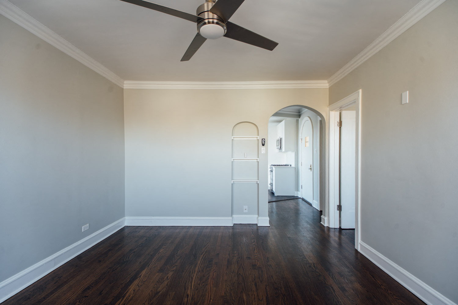 a living room with white walls and a ceiling fan