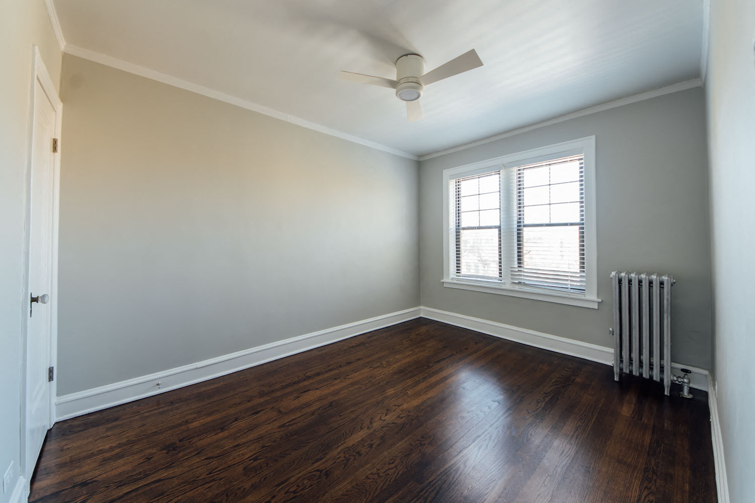 an empty room with wood floors and a ceiling fan