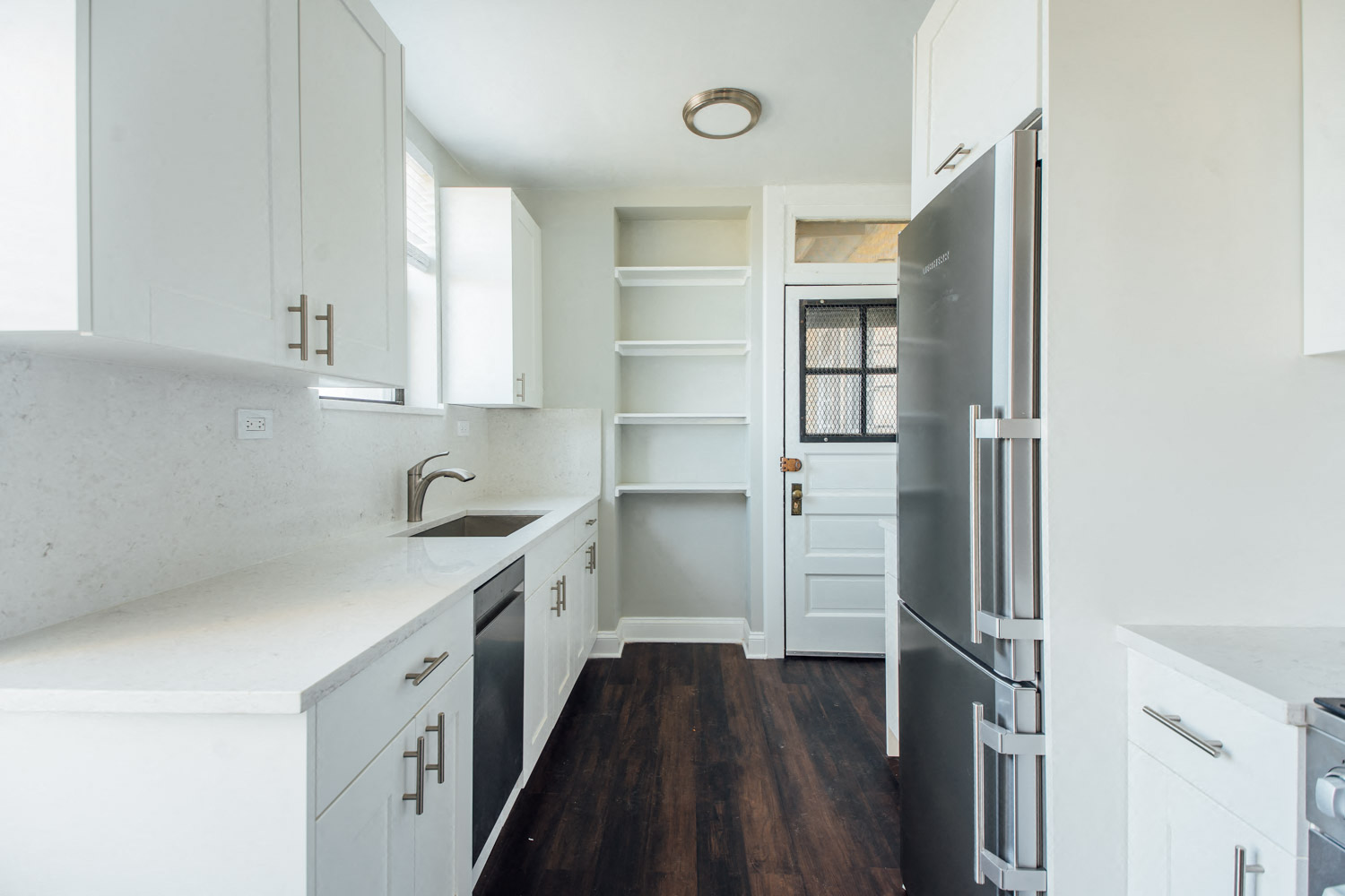 a kitchen with white cabinets and a black refrigerator