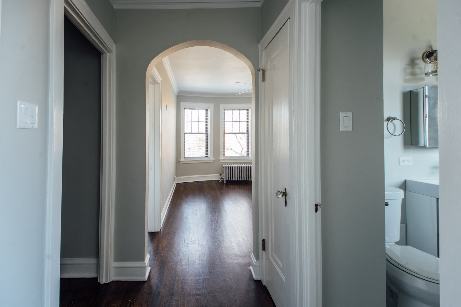 a hallway with an archway leading to a bathroom and a window