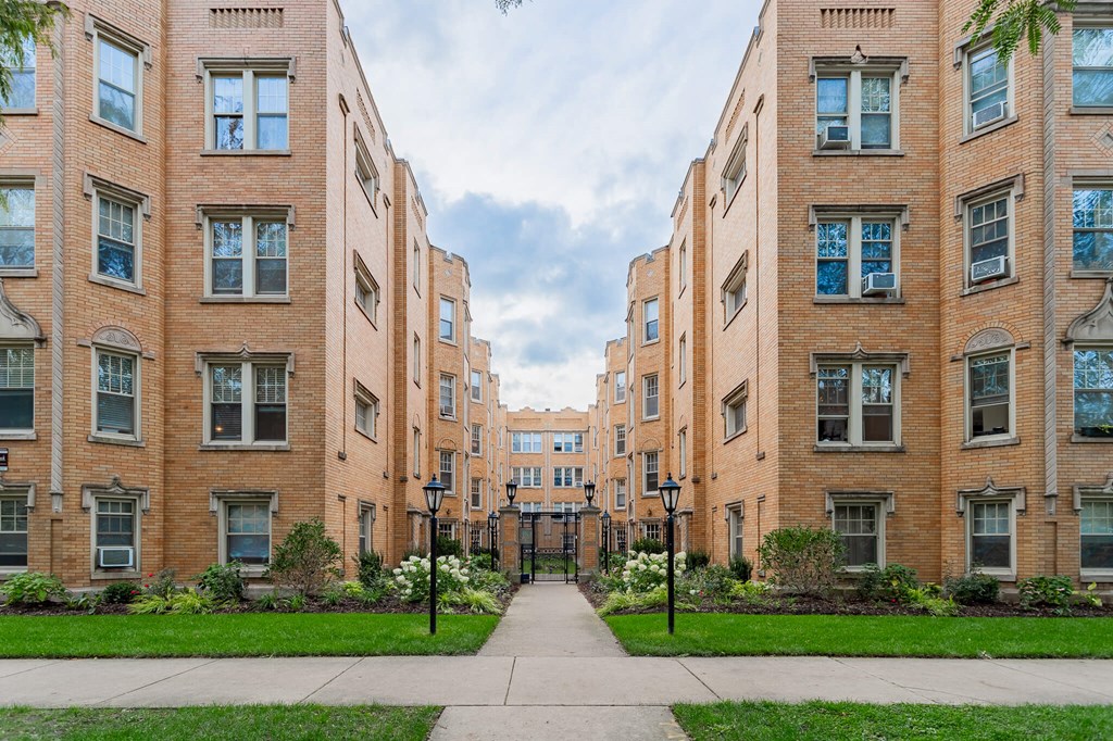a pathway between two brick apartment buildings with grass