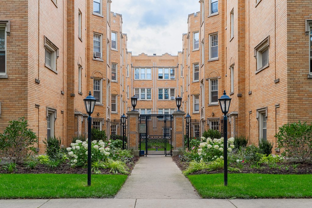 a sidewalk in front of a brick building with a gate