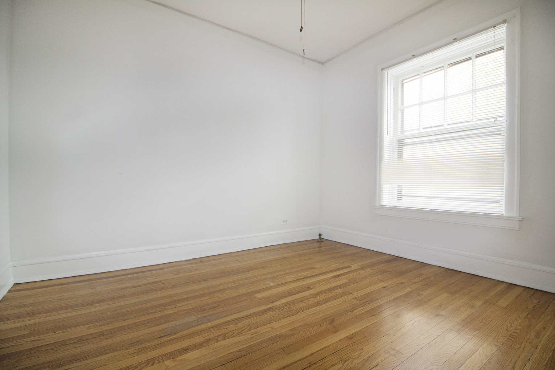 an empty room with wood floors and a window