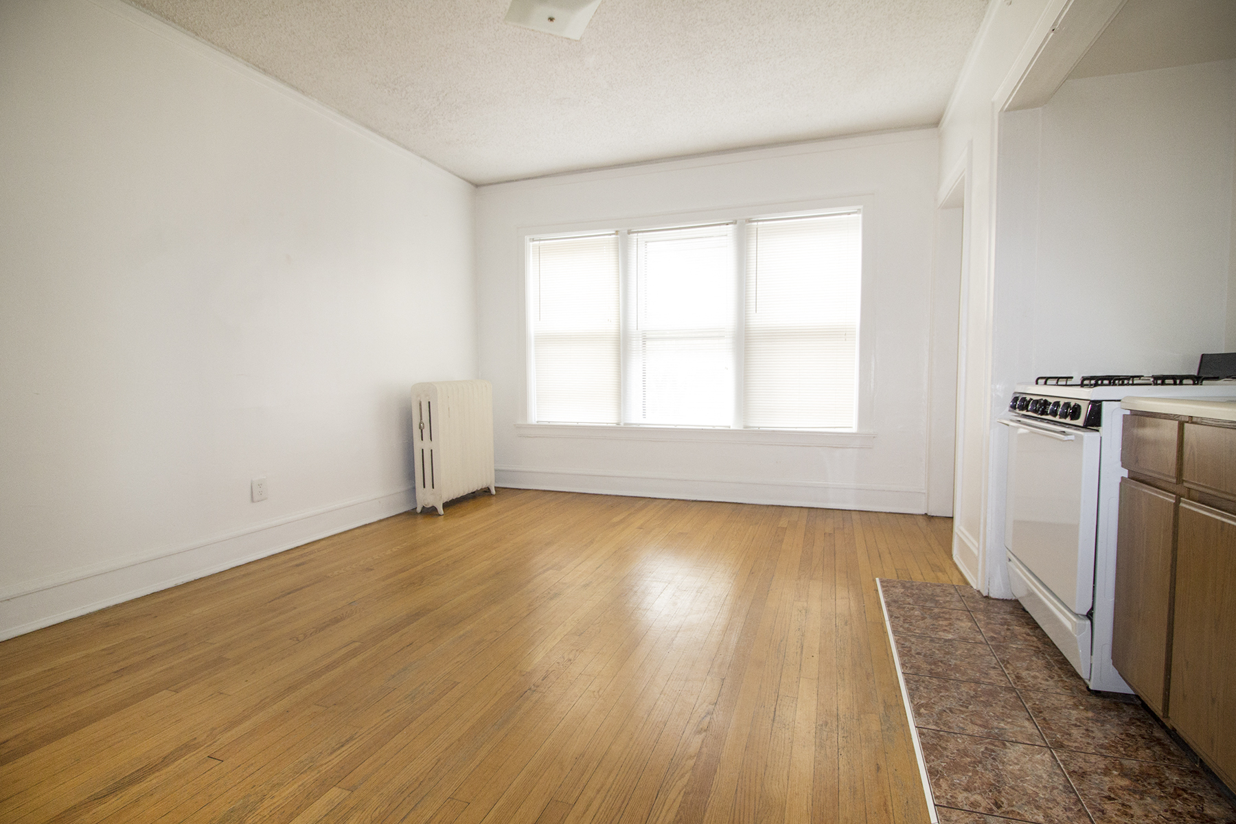 an empty kitchen with wood flooring and a stove and a window