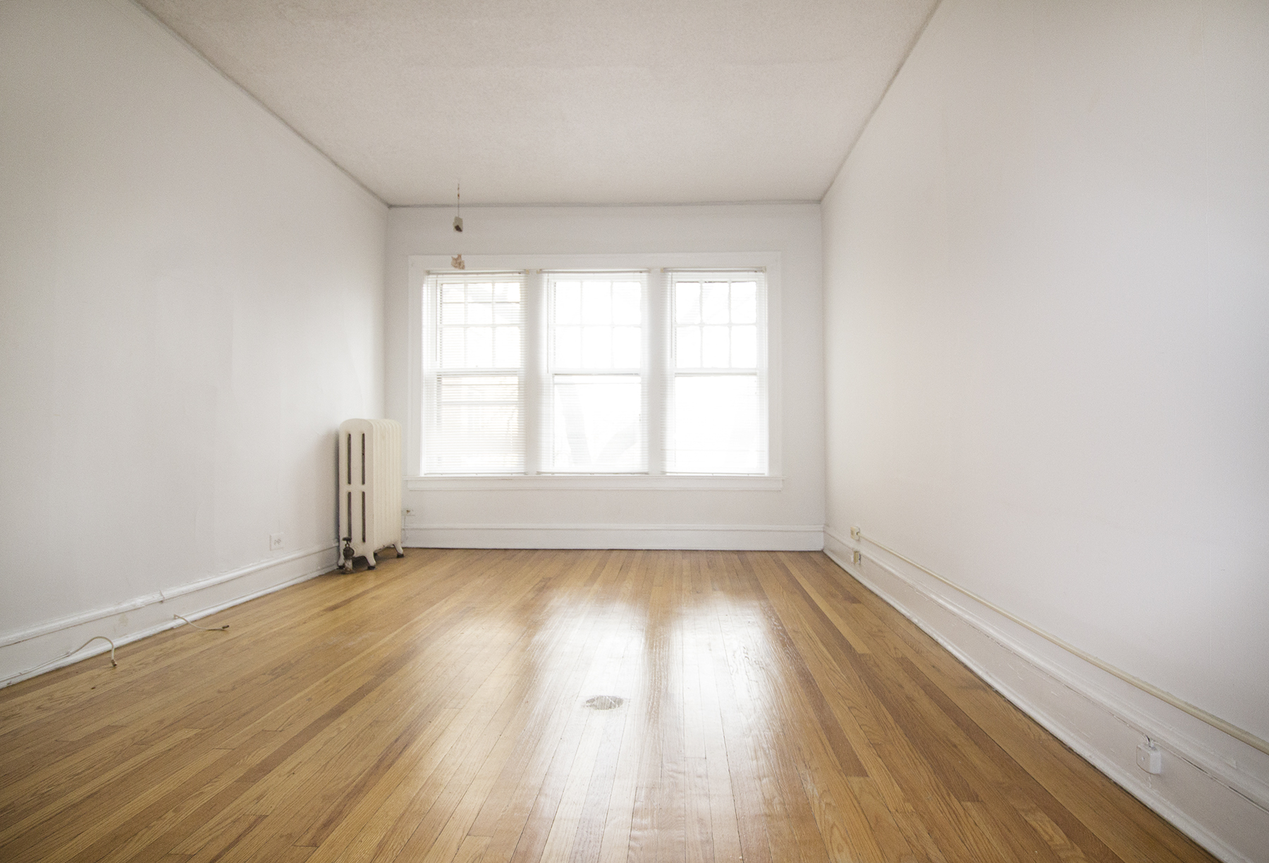 an empty room with white walls and wooden floors