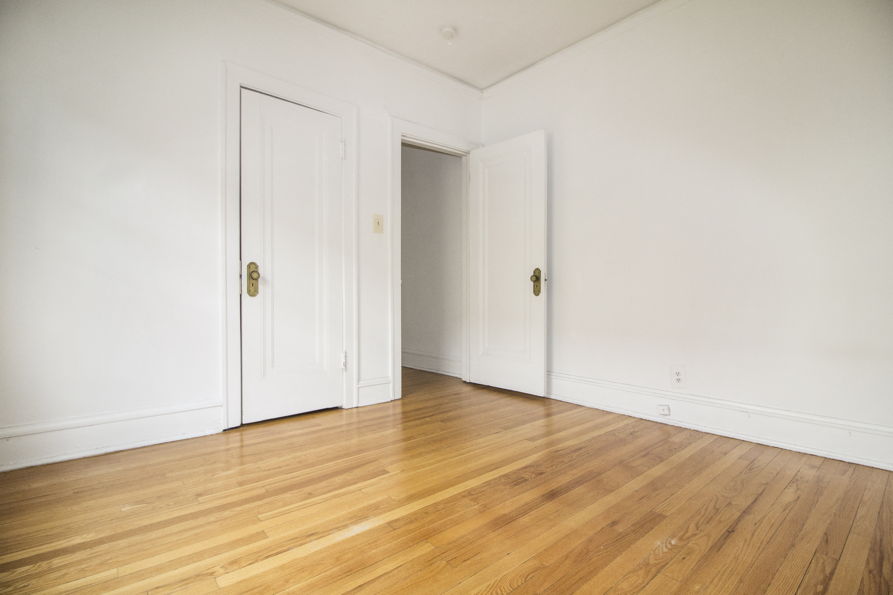 an empty room with white walls and wooden floors