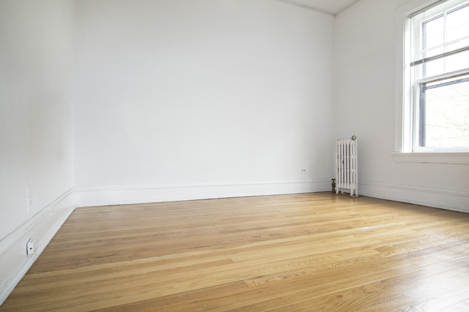 an empty room with white walls and wooden floors