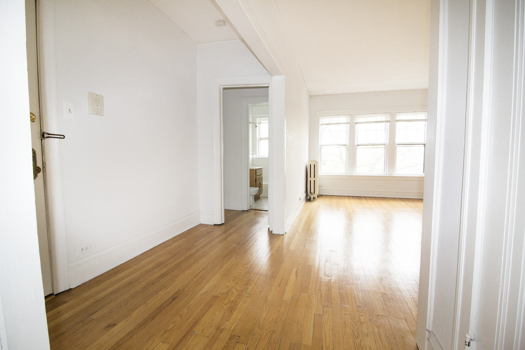 an empty living room with white walls and wood floors