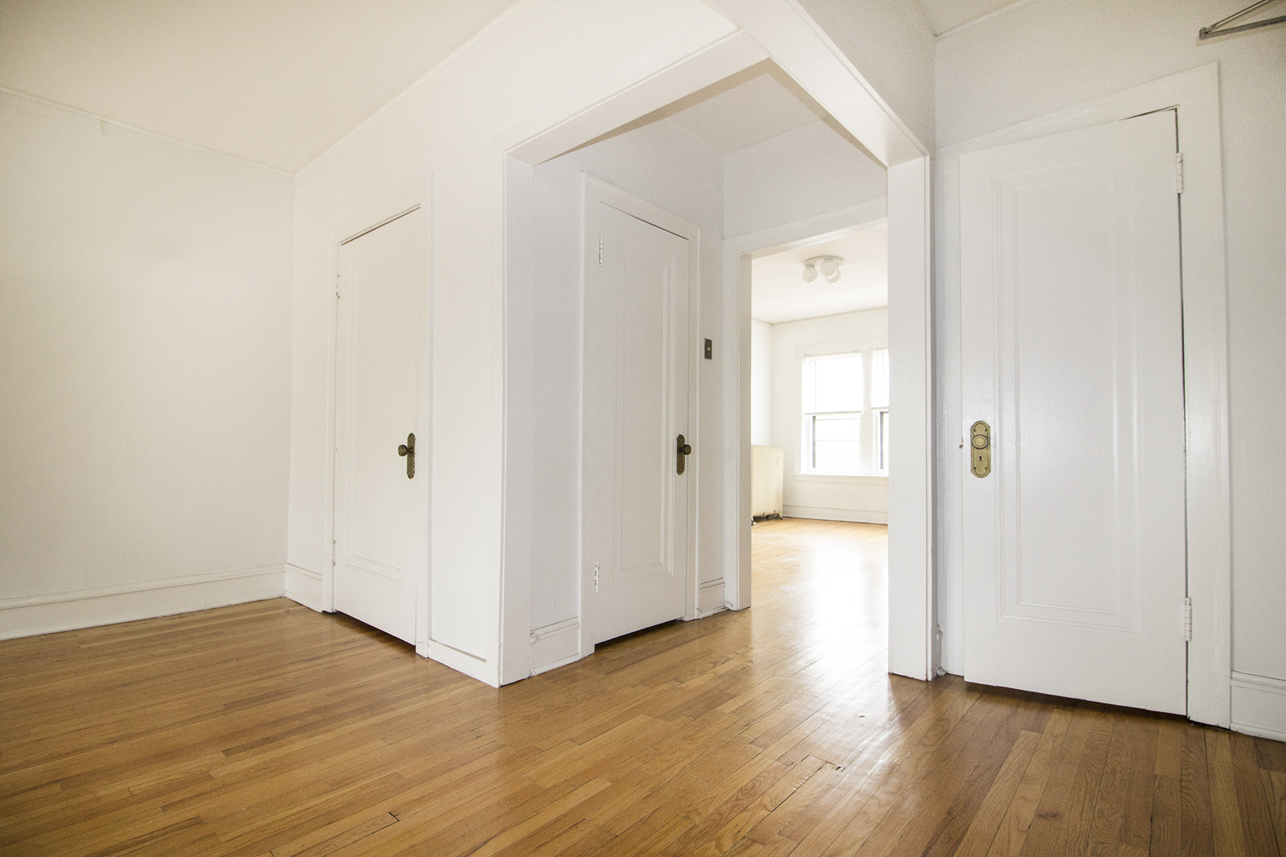 an empty room with white walls and wooden floors