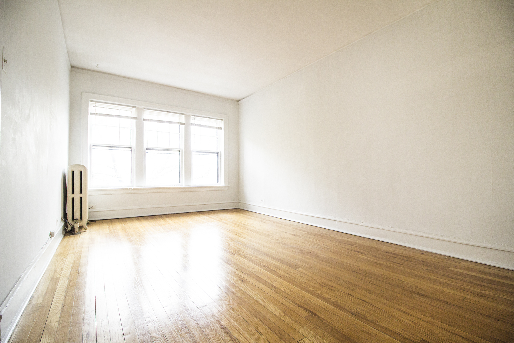 an empty room with wooden floors and a window