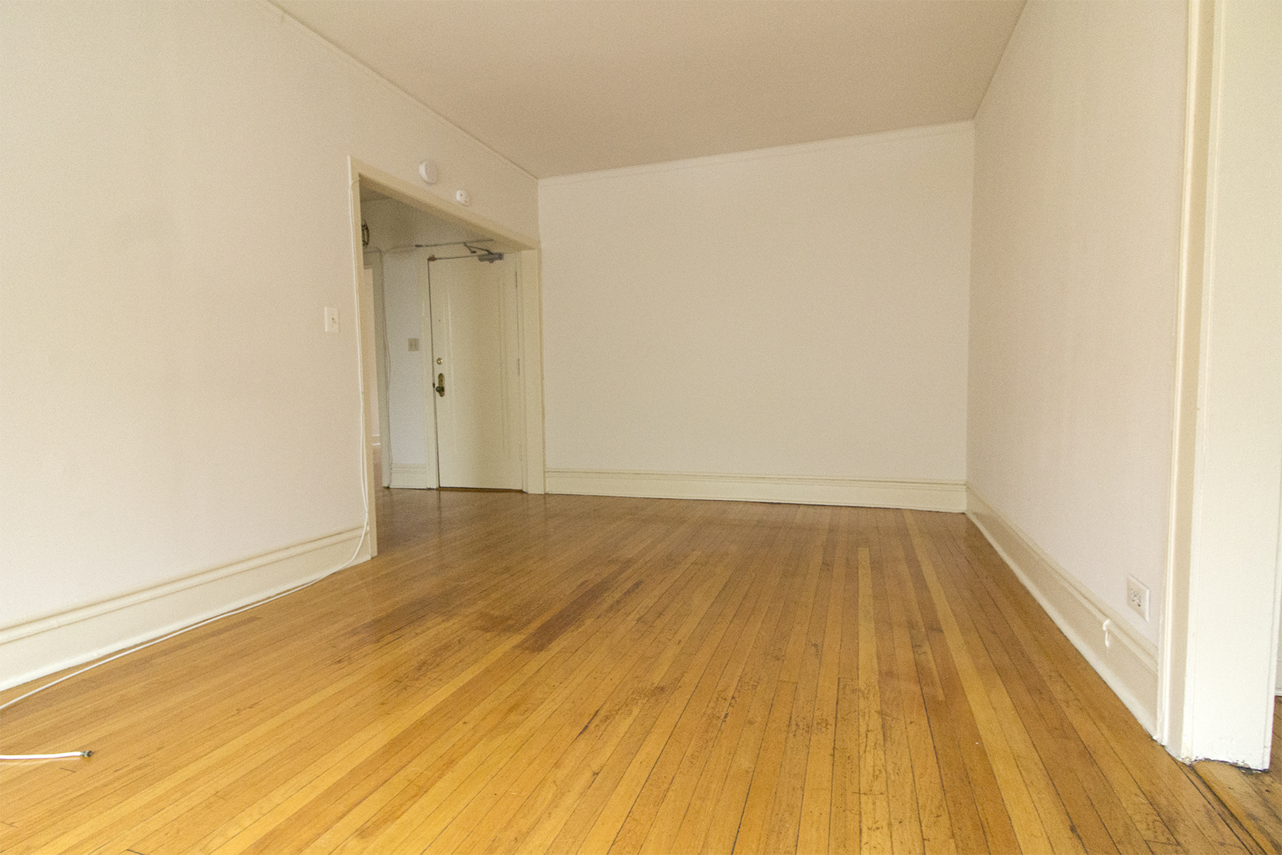 an empty living room with wood floors and white walls