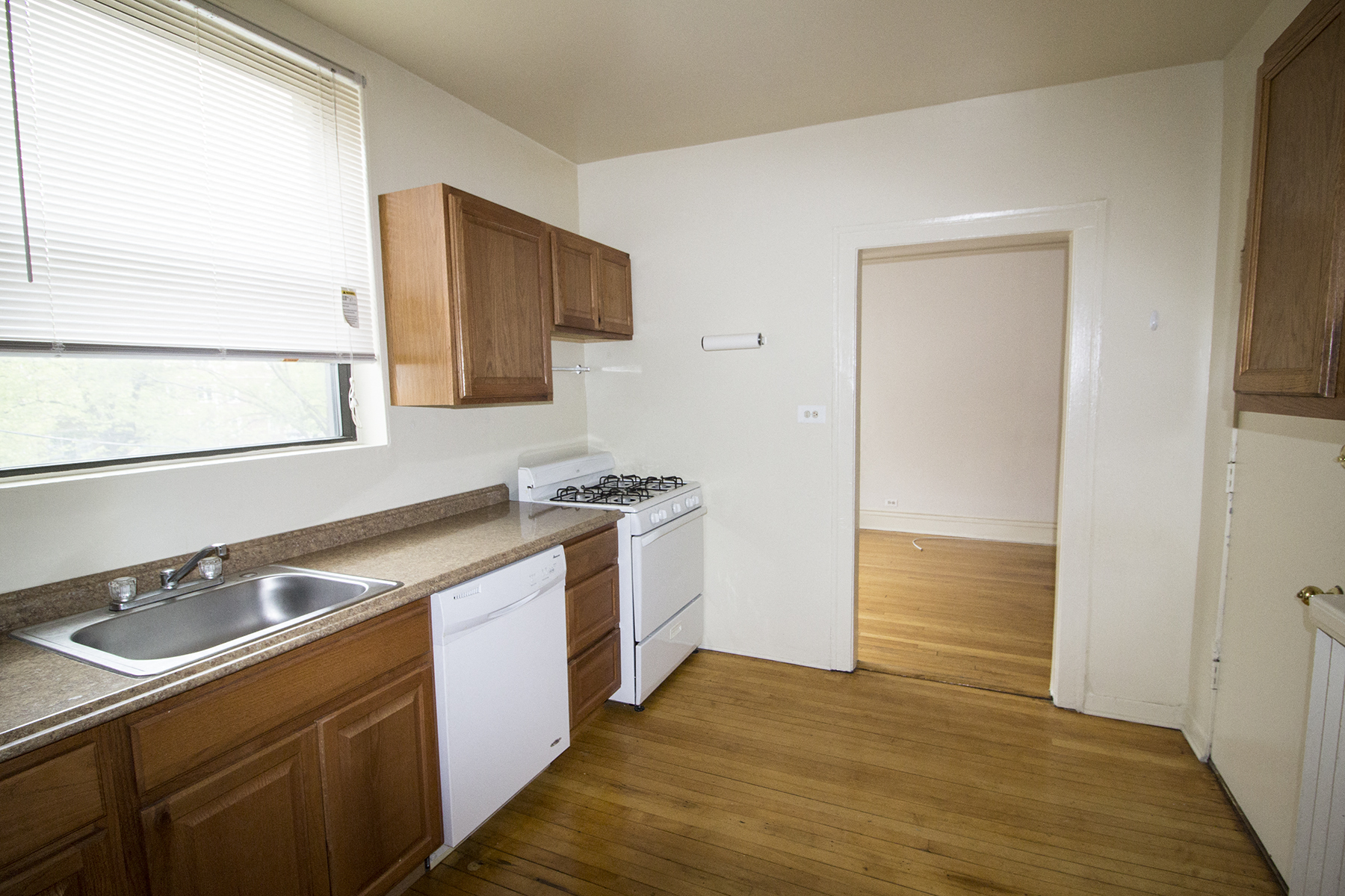 an empty kitchen with wood flooring and a sink and a window