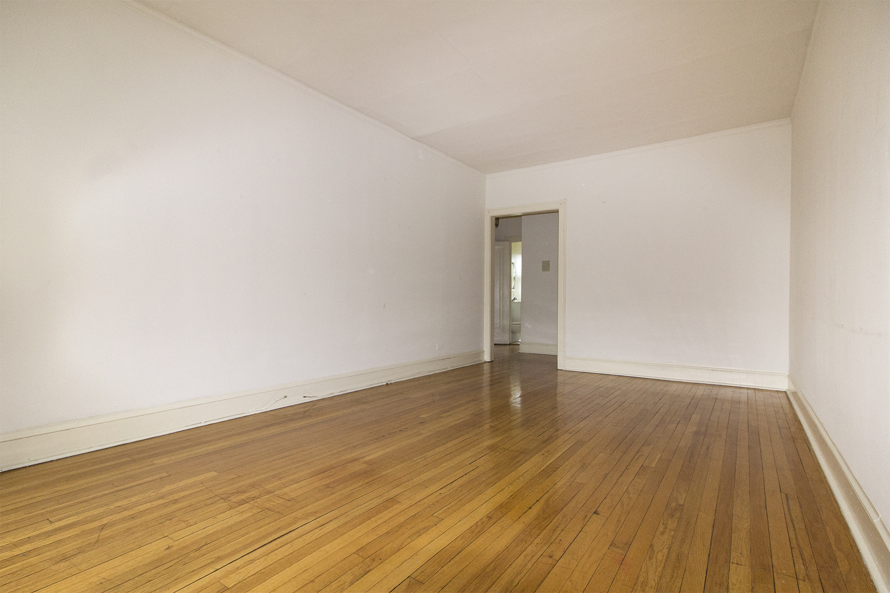 an empty room with white walls and wooden floors