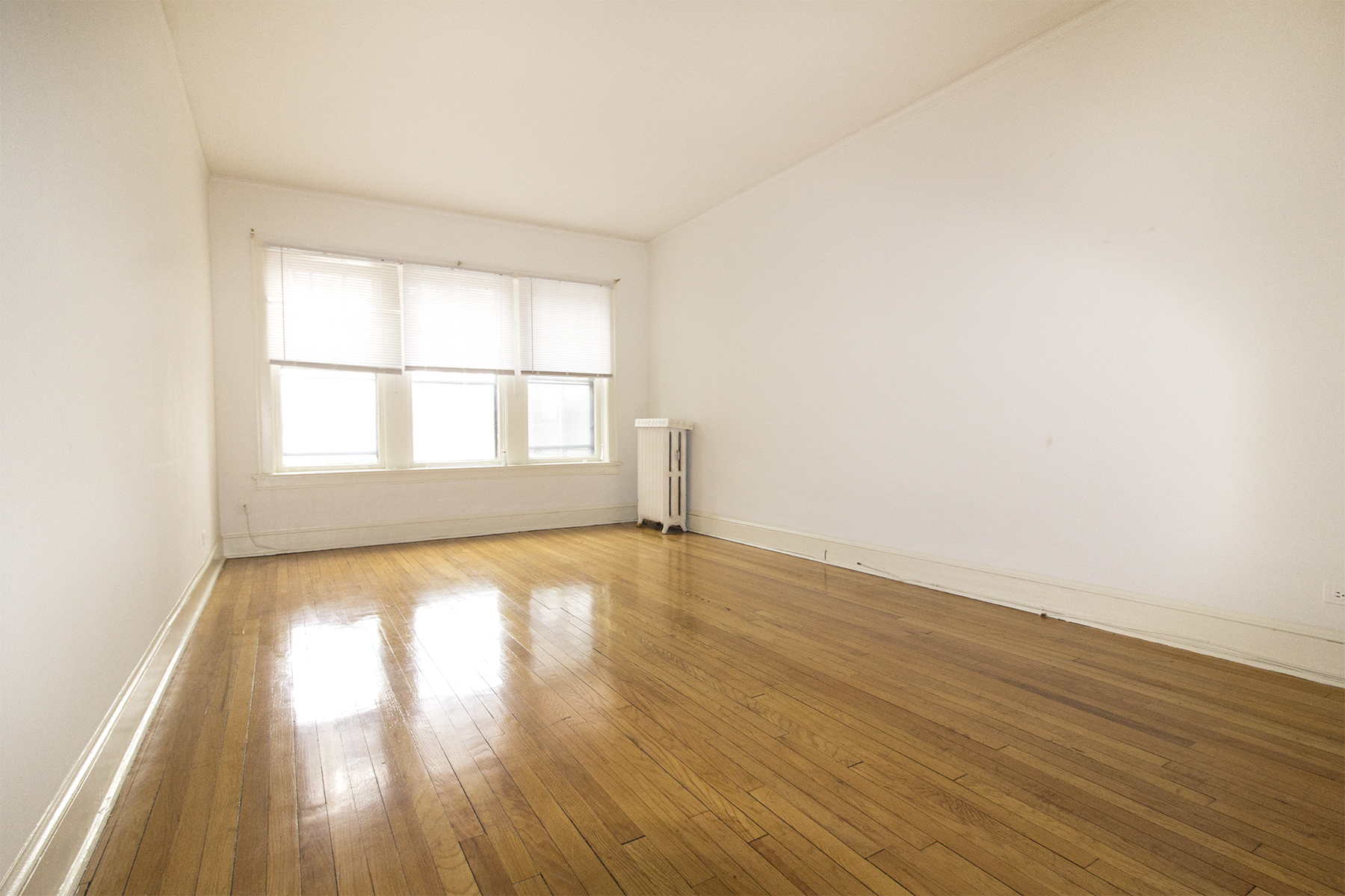 an empty room with wooden floors and a window