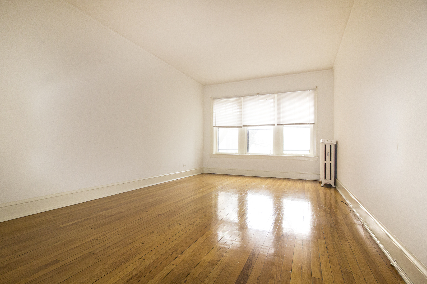 an empty room with wood floors and a window