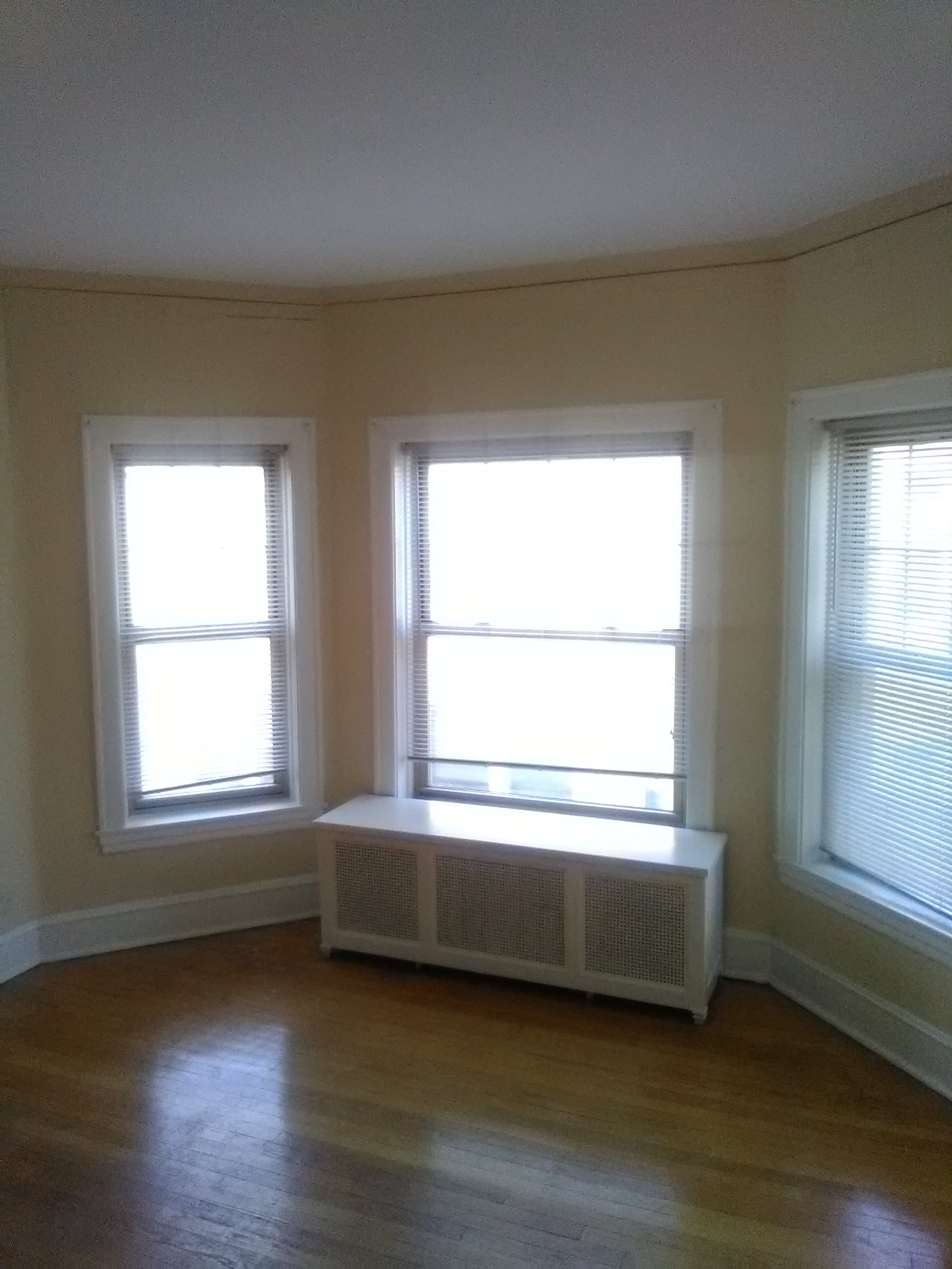 an empty room with a radiator and two windows