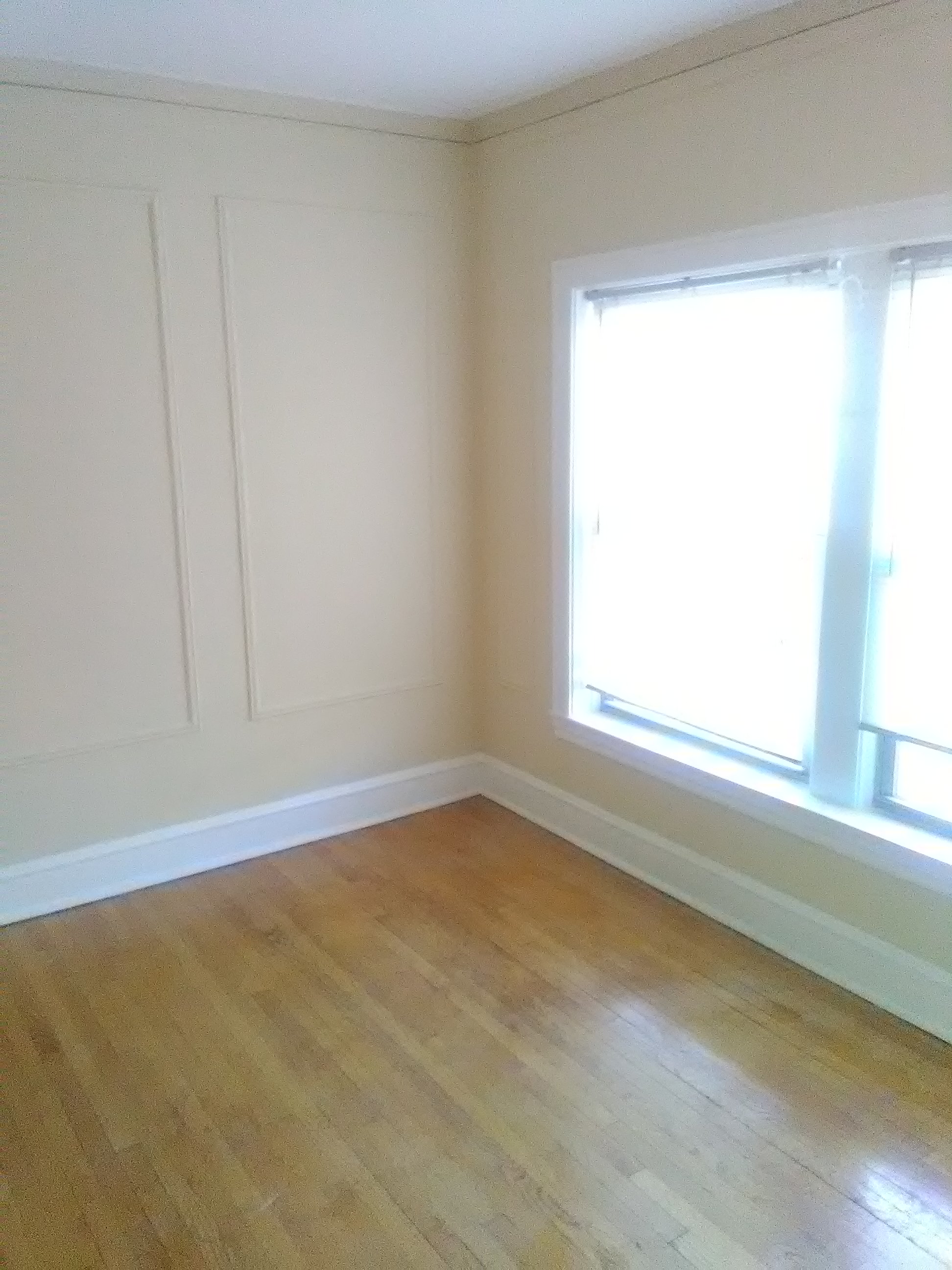 an empty room with two windows and a wooden floor