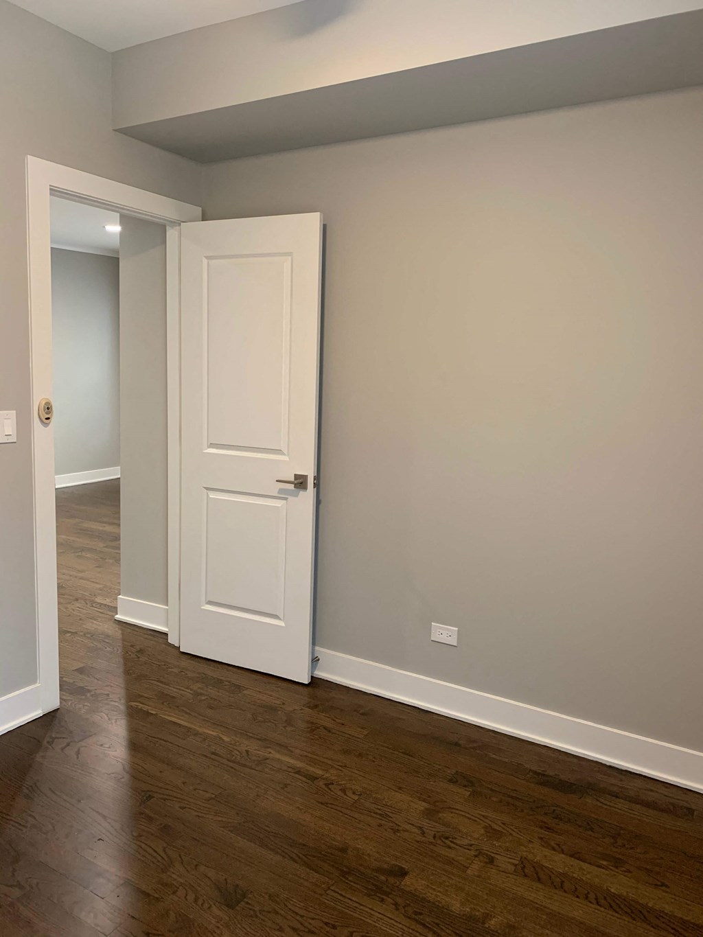 a room with a white door and a hallway with wood floors