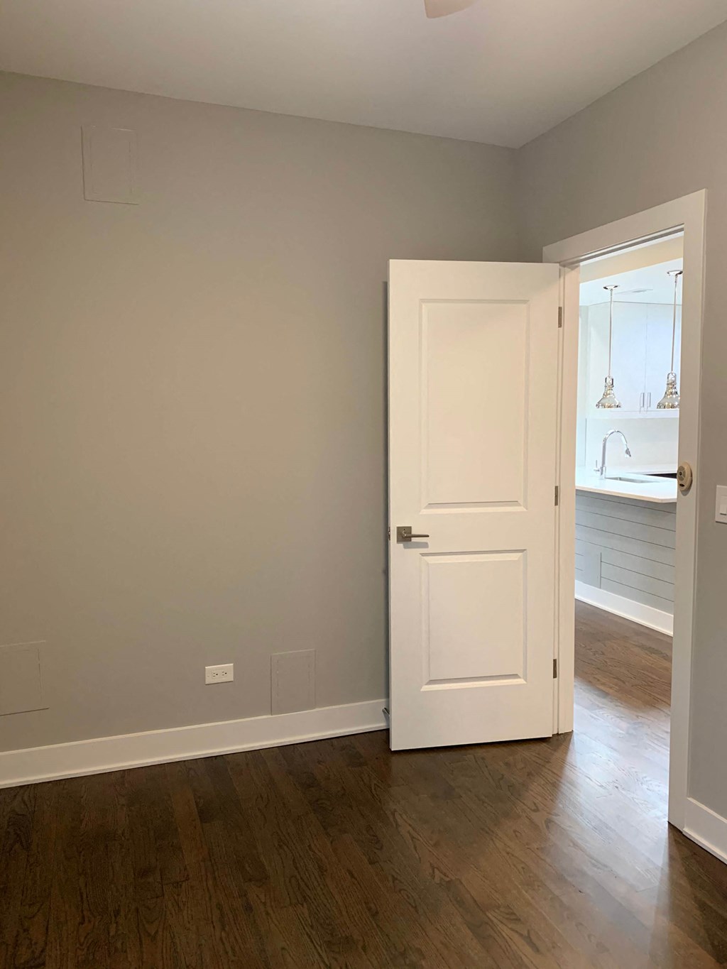 a white door in a room with wood floors and a bathroom