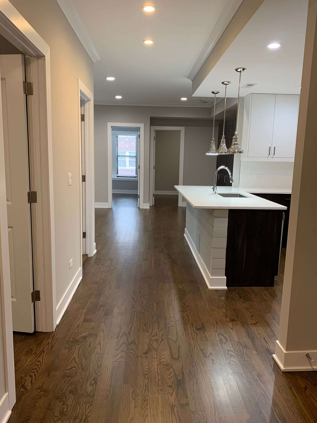 a renovated kitchen and living room with hardwood floors and white cabinets