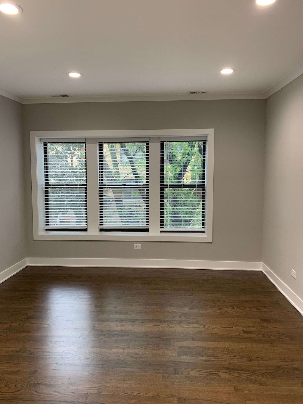 an empty living room with windows and wood floors