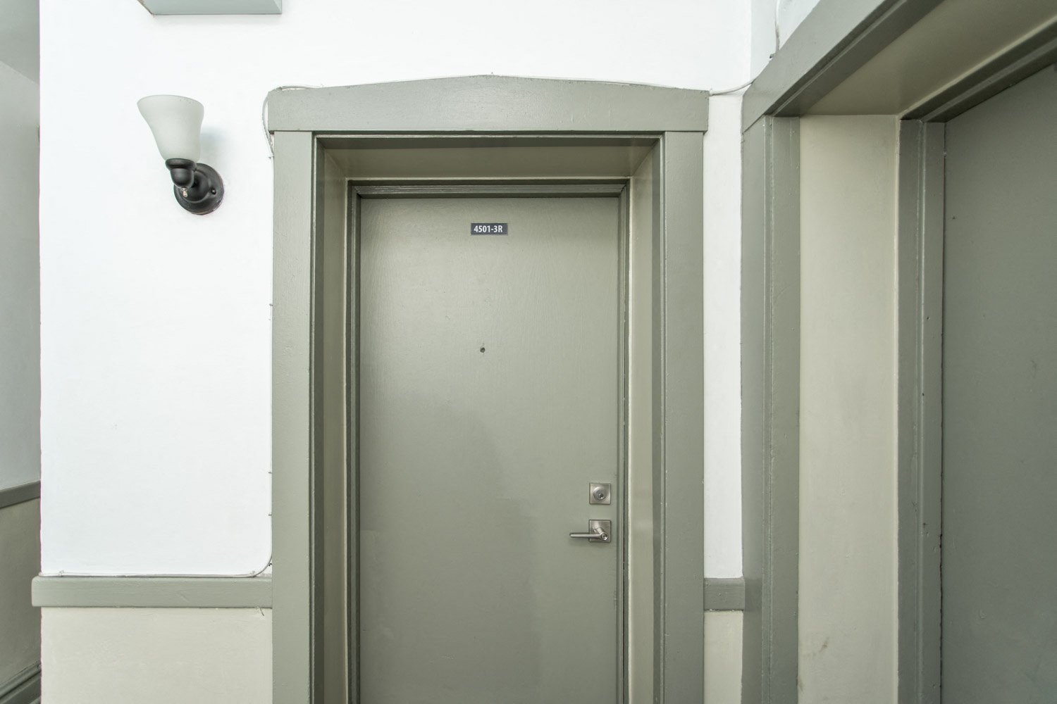 a white door with a gray doorframe and a white wall with an open door