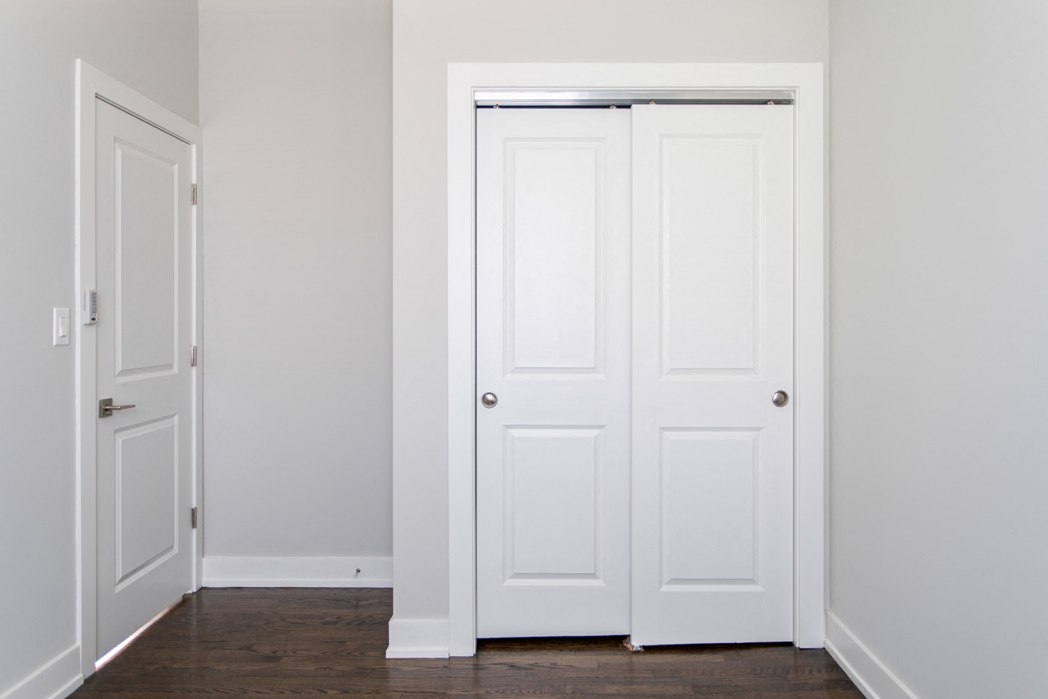 an empty room with white doors and a wood floor