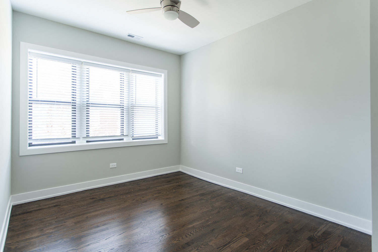 a room with wood floors and a window and a ceiling fan