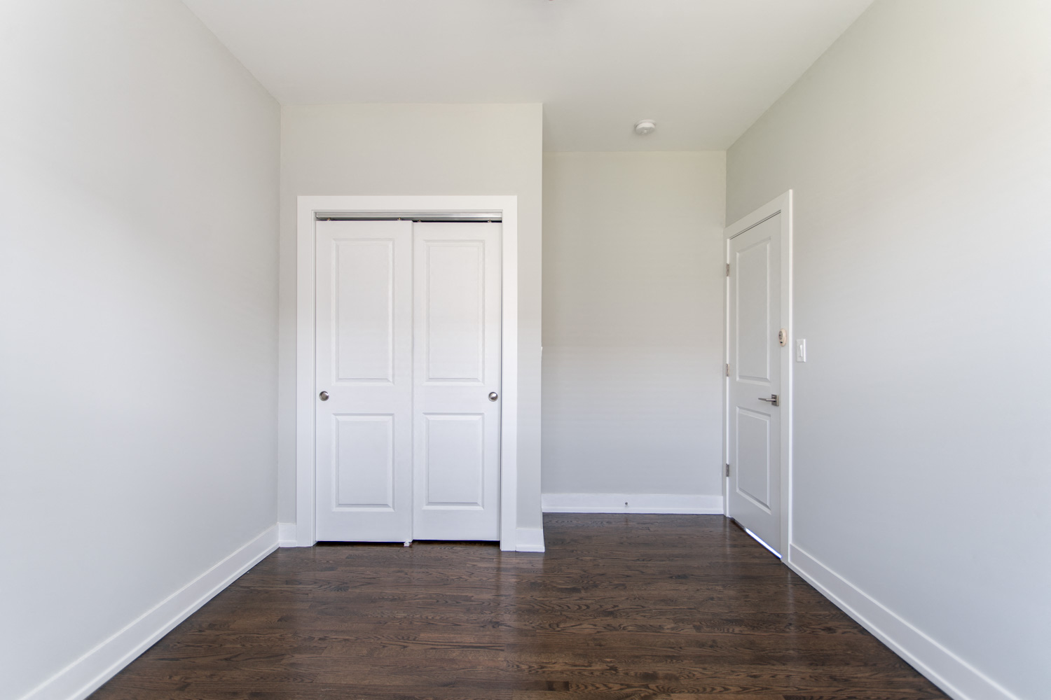 an empty room with white walls and wood floors and a white door