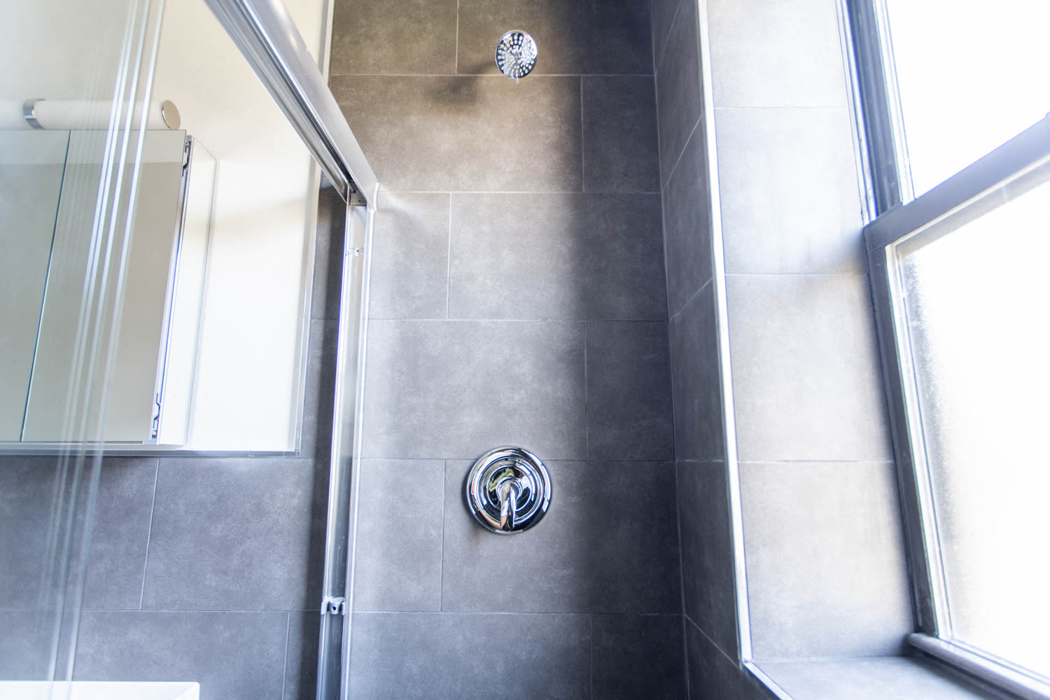 a grey tiled shower in a small bathroom