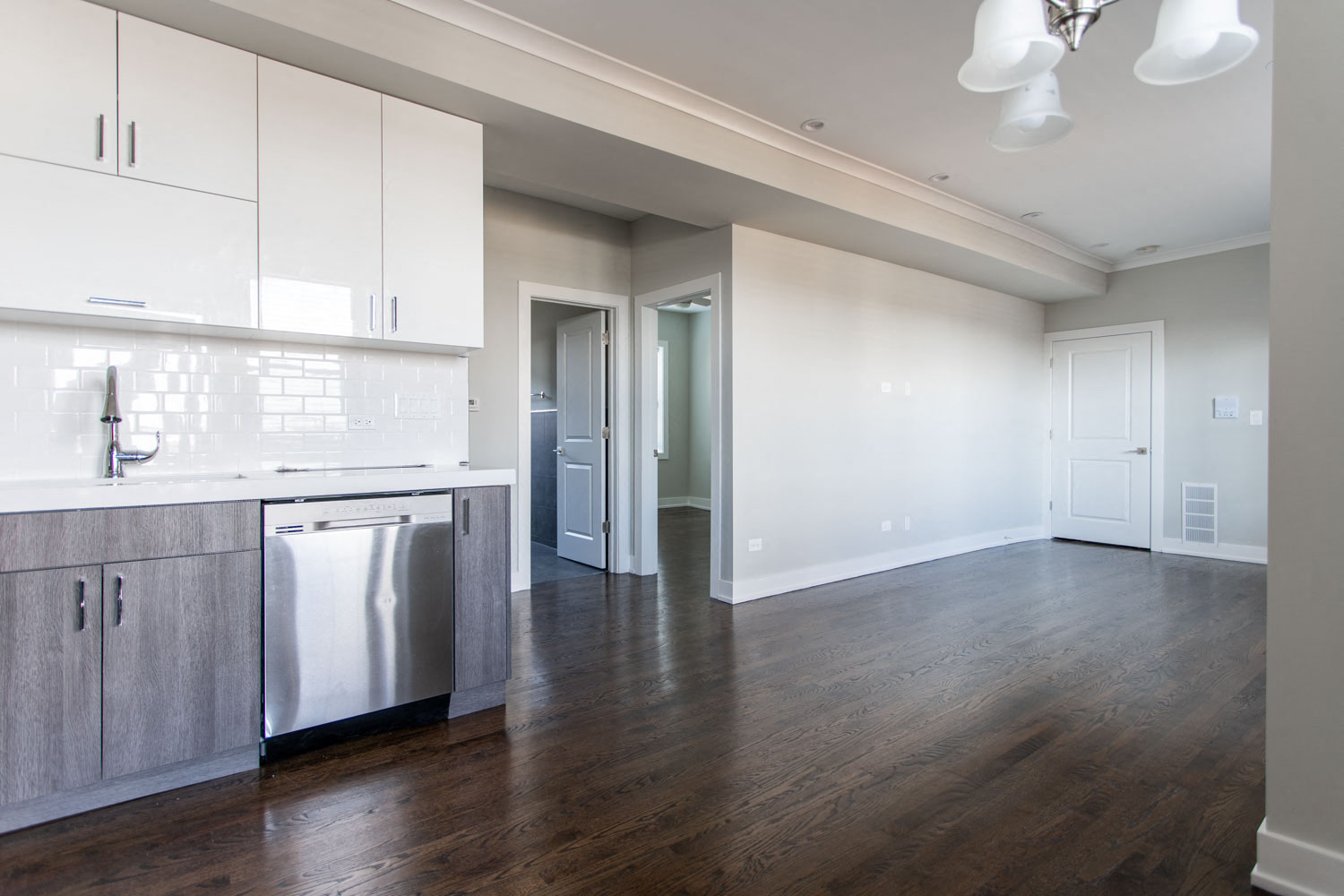 an empty kitchen and living room with white cabinets
