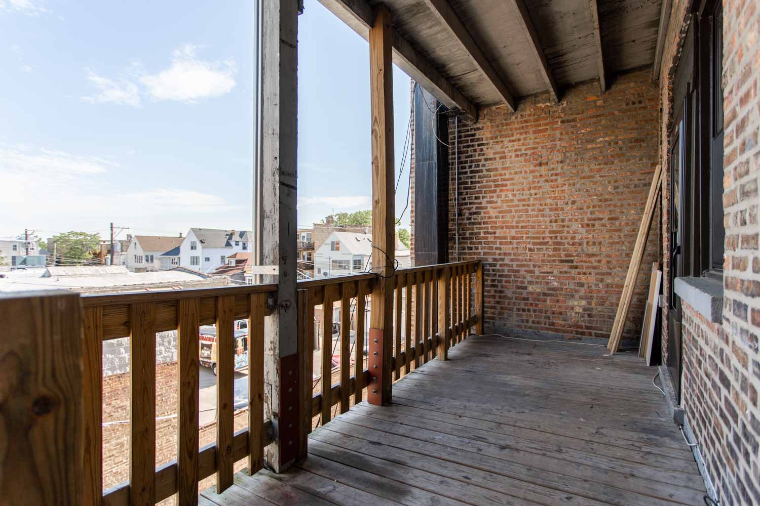 a balcony with a brick building and a wooden deck