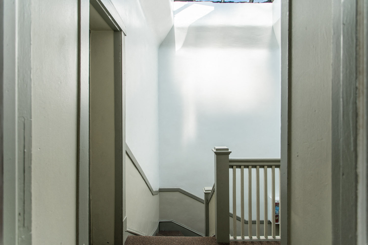 a stairwell with white walls and a stair railing and a window