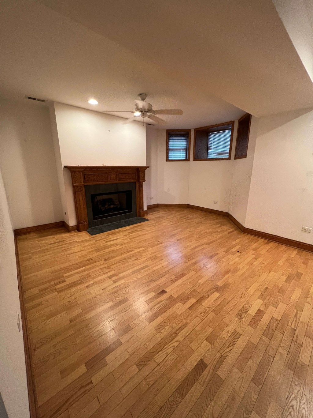 an empty living room with a fireplace and wooden floors