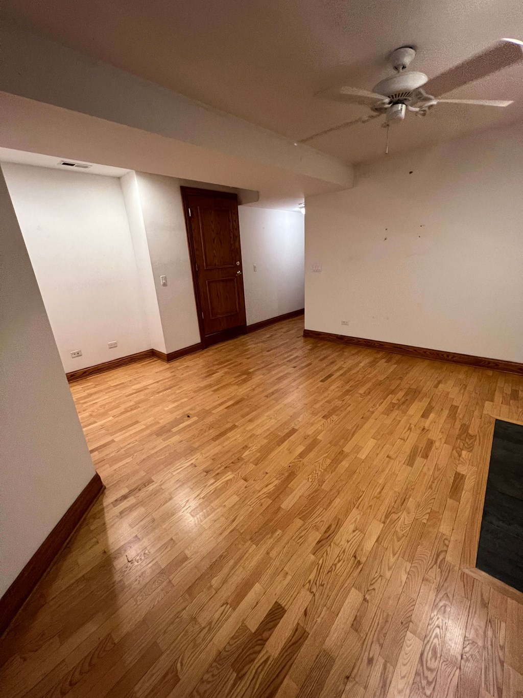 an empty living room with wooden floors and a ceiling fan