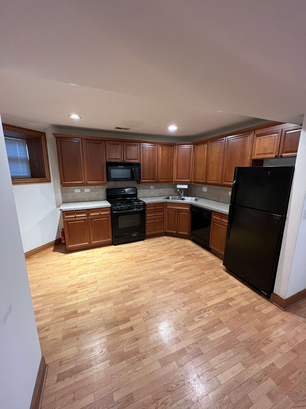 an empty kitchen with wooden floors and black appliances