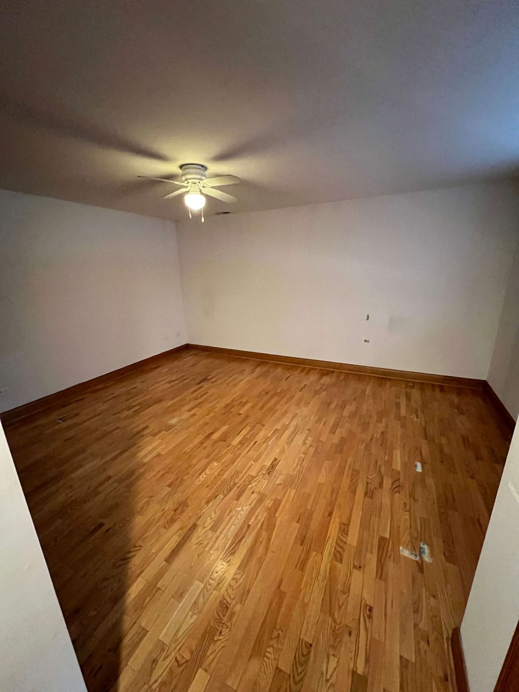 a empty room with wood floors and a ceiling fan