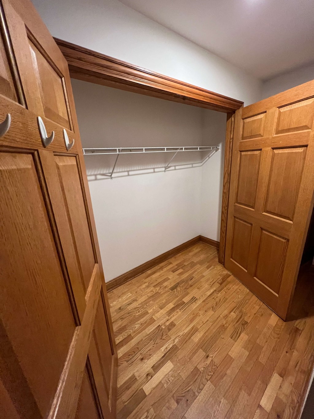 a room with a closet and a wooden floor and wooden doors