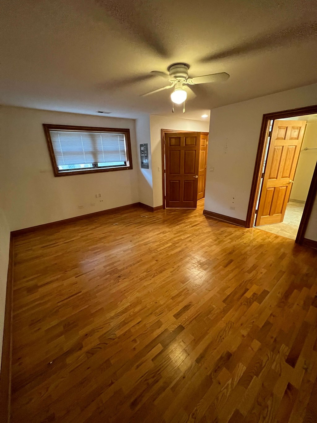 an empty living room with wooden floors and a ceiling fan