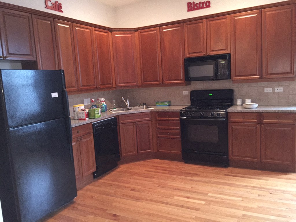 a kitchen with black appliances and wooden floors