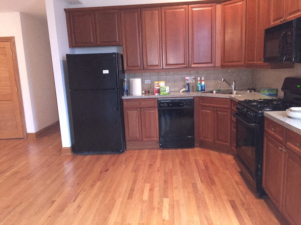 a kitchen with wooden floors and black appliances