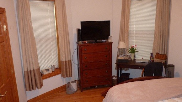 a bedroom with a dresser with a tv on top of it